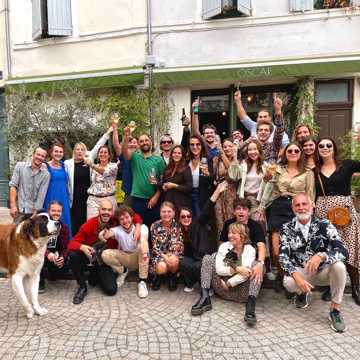 Grande tablée d'amis devant la façade d'Oscar