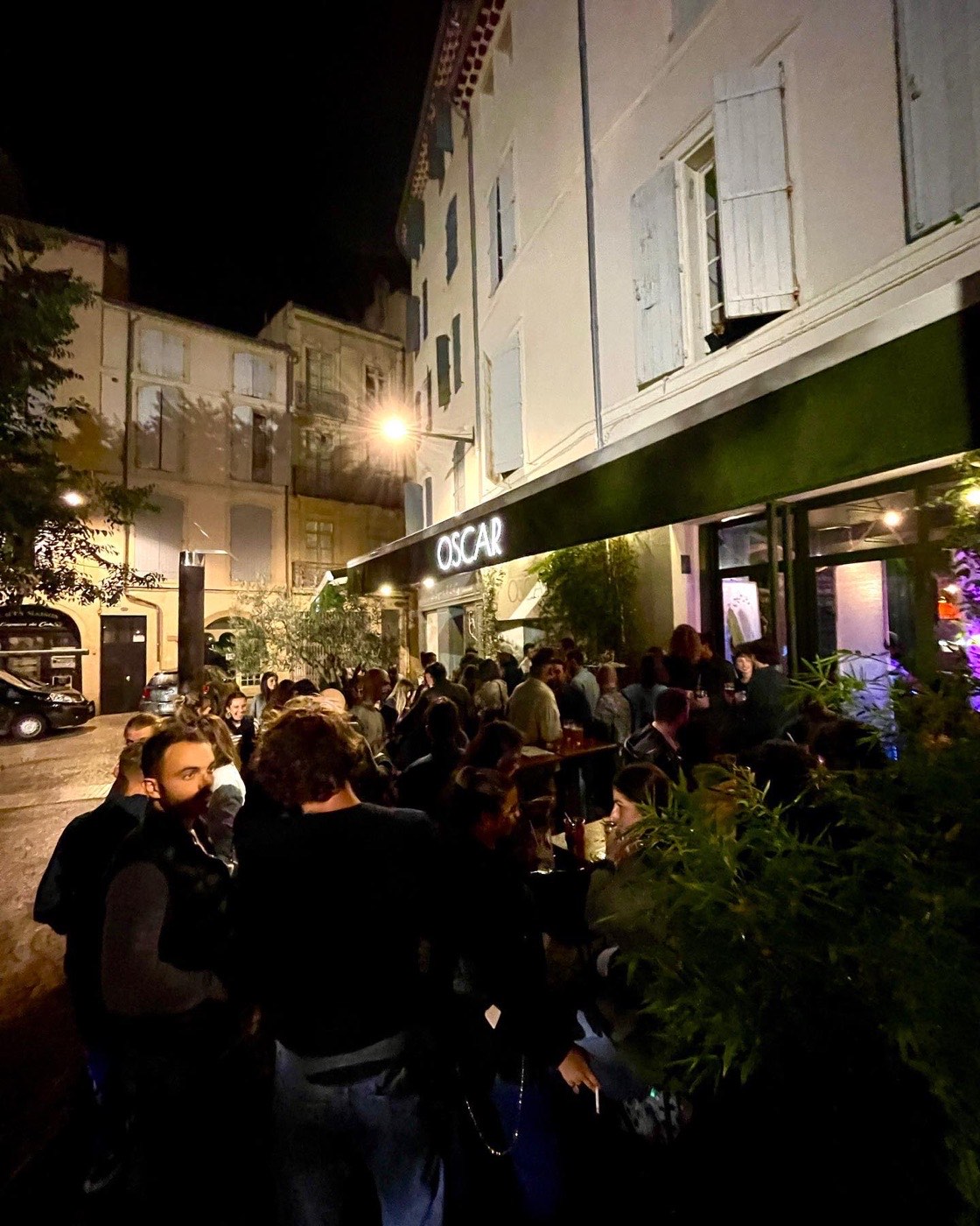 Foule animée en terrasse devant Oscar, le soir